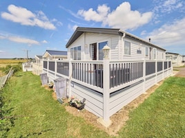 A mobile home with a fenced deck and a covered outdoor area.