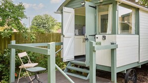 A small, single-room cabin with a wooden deck and a chair.