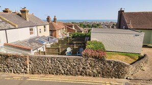 A residential area with stone walls, a paved road, and houses with varying roof styles. - Host Stay Old Stone Cottage (Hythe)