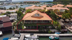 A coastal hotel with a red-tiled roof, a pool area, and a marina with boats. - Spanish Water Marina Triple Penthouse (Jan Thiel)