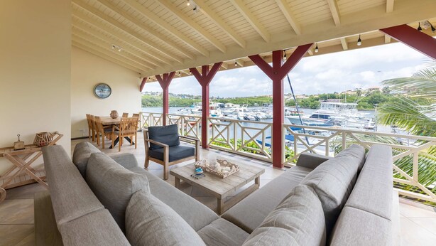 A covered outdoor seating area with a view of boats and greenery. - Spanish Water Marina Triple Penthouse (Jan Thiel)