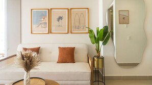 Una sala de estar moderna con un sofá, un espejo grande y obras de arte enmarcadas en la pared.
