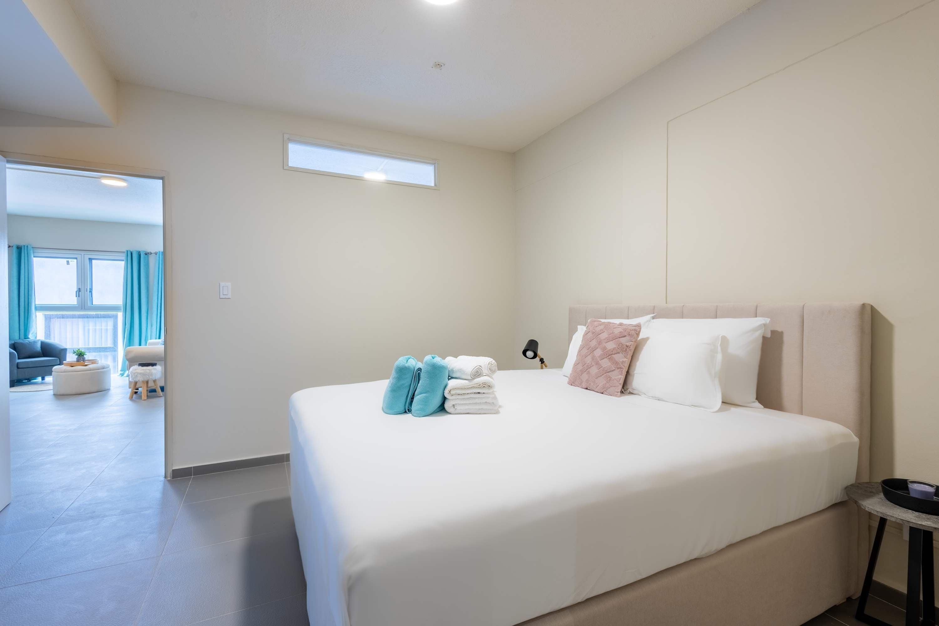 A hotel room with a large bed, a small round table, and a view of the living area.