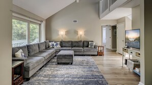 A spacious living room with a sectional sofa, a large rug, and a television.