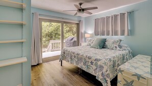 A bedroom with a bed, a ceiling fan, a window with curtains, and a view of the outdoors.