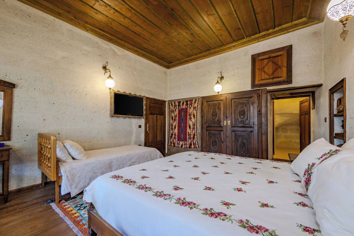 Ein Schlafzimmer mit zwei Betten, Holzbalkendecke und einem Wandbehang mit Muster.
