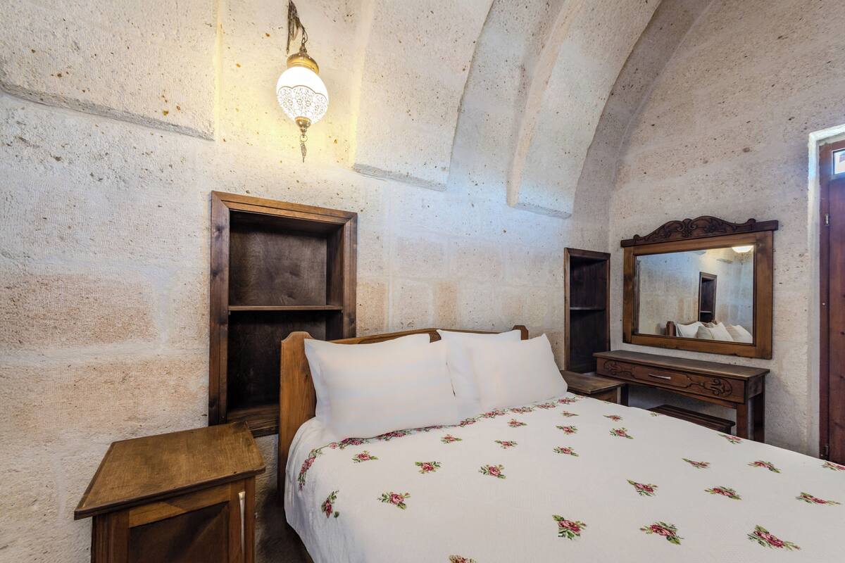 Ein Schlafzimmer mit einem hölzernen Bett, einem Nachttisch, einer Kommode und einem Spiegel.