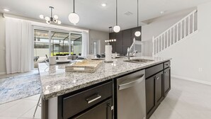 A modern kitchen with granite countertops, stainless steel appliances, and pendant lighting.