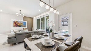 A modern dining area with a table set for four, a gray sofa, and a large window.