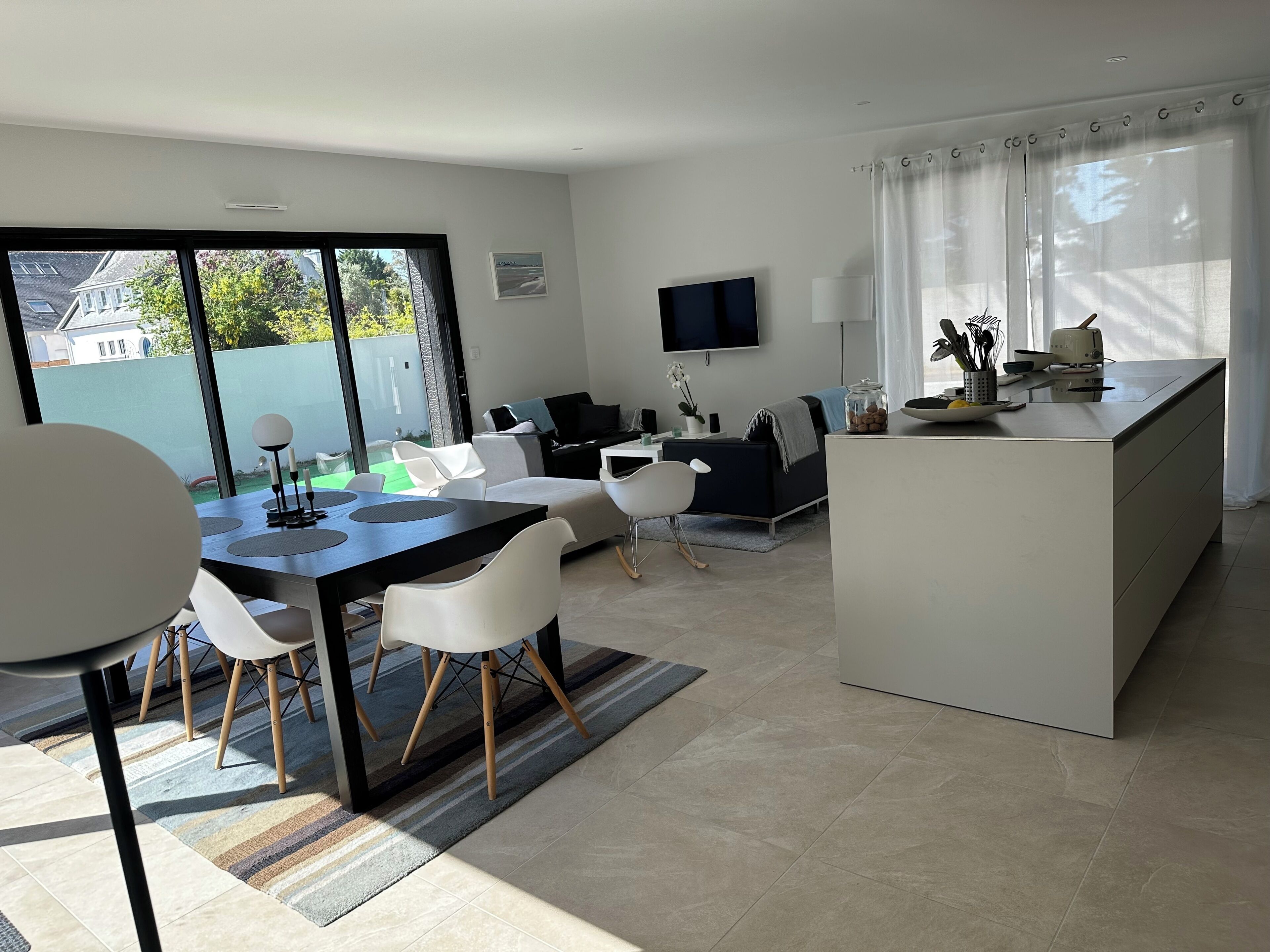 Un espace de vie moderne comprenant un coin repas, un canapé, un téléviseur et un îlot de cuisine.