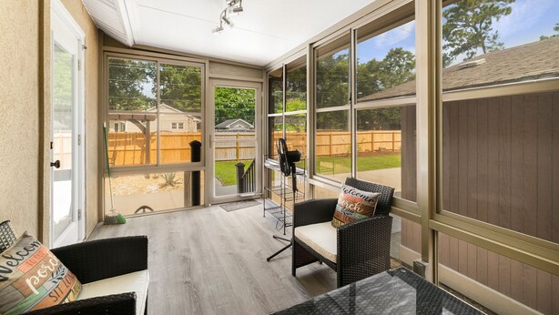 A sunroom with large windows, a ceiling fan, and a seating area with a table and chairs.