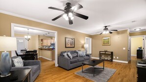 A spacious living room with hardwood flooring, a gray sofa, a coffee table, and a ceiling fan.