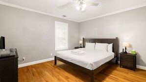 A bedroom with a bed, nightstands, a ceiling fan, and a window with blinds.
