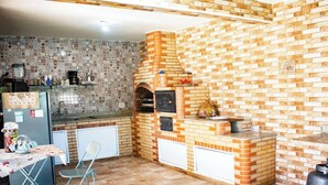 Una cocina compacta con pared de ladrillo, horno empotrado y un pequeño comedor con mesa y sillas.