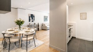 A modern dining area with a round table, chairs, and a vase of flowers. - 1600 Lecourbe (Paris)