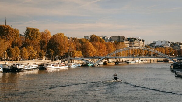 A river with boats, a bridge, and autumn trees.