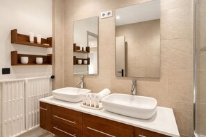 A modern bathroom with two sinks, wooden cabinets, and a large mirror.