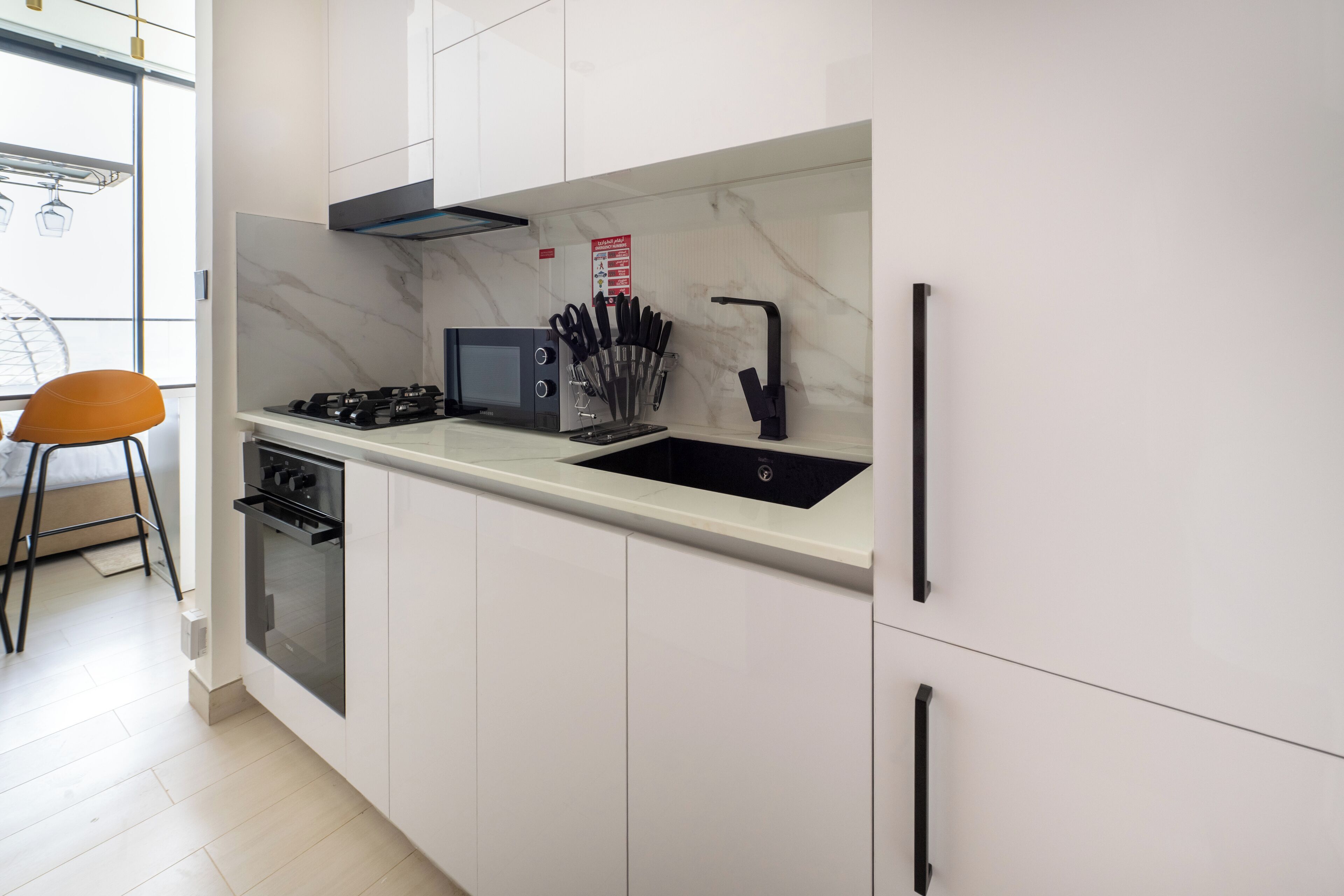 Cocina moderna con gabinetes blancos, estufa negra, un lavamanos y un juego de cuchillos.