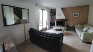 A living room with a black sofa, a white sofa, a coffee table, and a fireplace. - South Corsica house, close to the most beautiful beaches and mountains (Sotta)