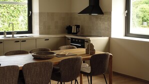 Une cuisine moderne avec une table et des chaises en bois, un four encastré et une fenêtre donnant sur un paysage verdoyant.
