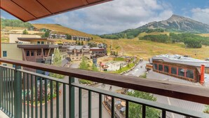 A view from a balcony overlooking a resort area with buildings, a road, and a mountain in the background.