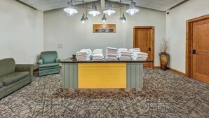 A room with a yellow reception desk, a green armchair, a wooden door, and a patterned carpet.