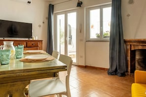 A dining area with a table set for two, a television on the wall, and a fireplace.