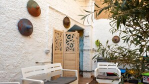 A courtyard with white walls, a wooden door, and two white chairs with cushions. - Holiday Home 'Barbara' with Private Garden, Wi-Fi and Air Conditioning (Teulada)