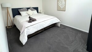 A bedroom with a bed, a nightstand, a floor lamp, and a wall art piece.