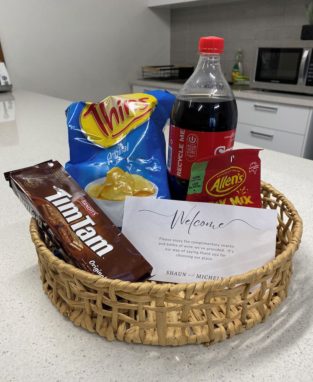 Eine Korb mit Snacks, einer Colaflasche, einer Schokoladenriegel und einer Dankeskarte.