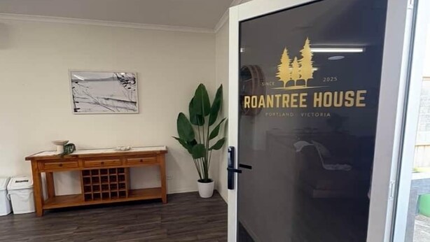 A modern interior with a wooden bench, a potted plant, and a glass door with a logo.