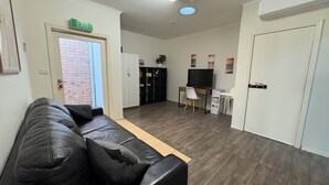 A modern interior with a leather sofa, a TV, a desk, and a bookshelf.