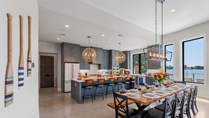 A modern kitchen with a central island, bar stools, and pendant lighting.