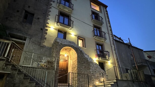 A multi-story building with a stone archway entrance, balconies, and exterior lighting. - Maripetra B&B (Sangineto)