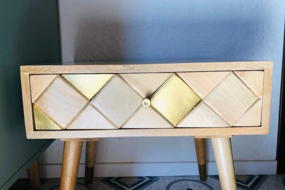 A wooden side table with a geometric pattern and a central knob.