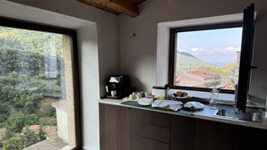 A kitchen with a coffee machine, a sink, and a window overlooking a mountainous landscape. - Maripetra B&B (Sangineto)