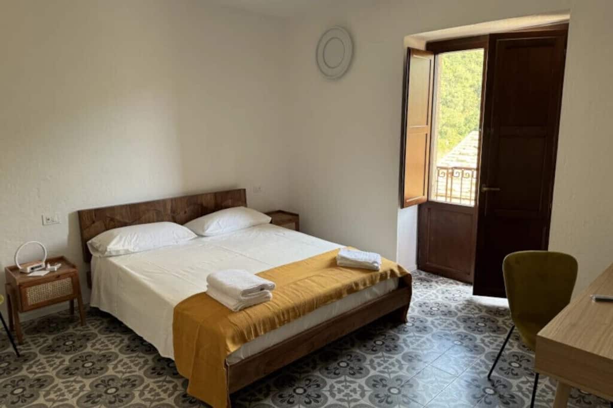 A bedroom with a bed, bedside table, and a chair.