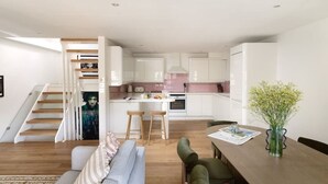 Un intérieur moderne comprenant un escalier, une cuisine, un coin repas et un salon.