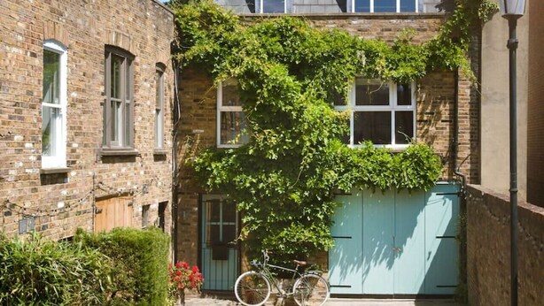 Une ruelle étroite avec un bâtiment en briques, un vélo et un portail bleu.