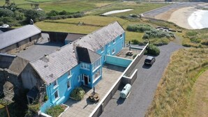 Ein zweistöckiges blaues Haus mit befestigter Auffahrt und einem kleinen Garten.