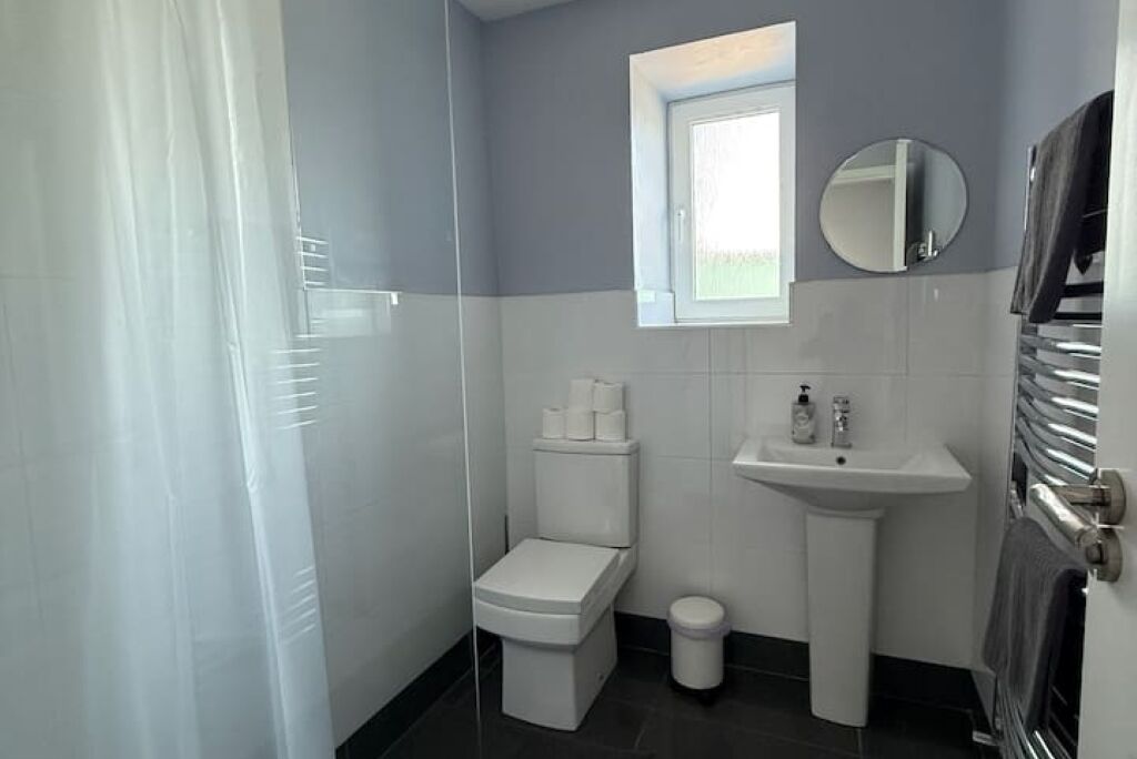 A bathroom with a toilet, sink, and a small window.