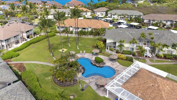 A residential area with a swimming pool, houses, and a cruise ship in the background. - Kona Sea Ridge#Y22: Beautiful Top Floor unit with Ocean Views in Gated area (Kailua Kona)