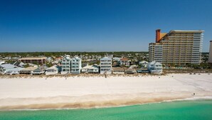 A coastal hotel with multiple buildings, a sandy beach, and clear turquoise waters. - Joy By The Sea 5 Bedroom Home (Panama City Beach)