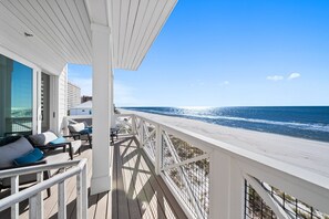 A balcony with a view of the beach and ocean.