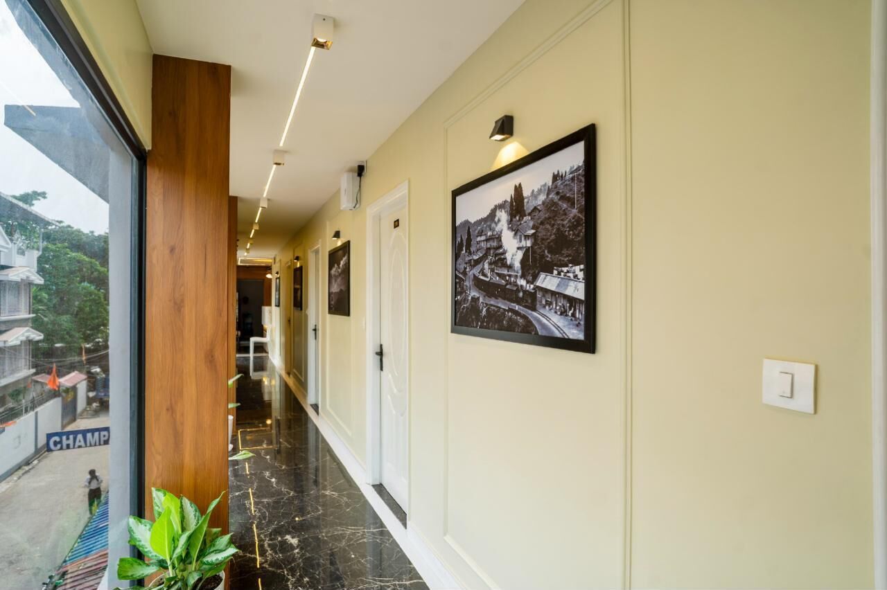 A hotel corridor with a wooden column, black and white photographs on the wall, and a view of the outside.
