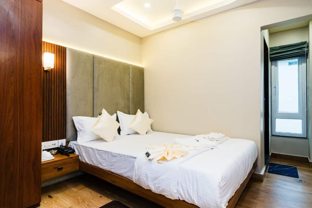 A hotel room with a bed, bedside table, and a wall-mounted light fixture.