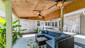A covered patio area with a wicker sofa, a coffee table, and a ceiling fan. - 4BR Home Yard, Patio, Near Beach and UNCW (Wilmington)