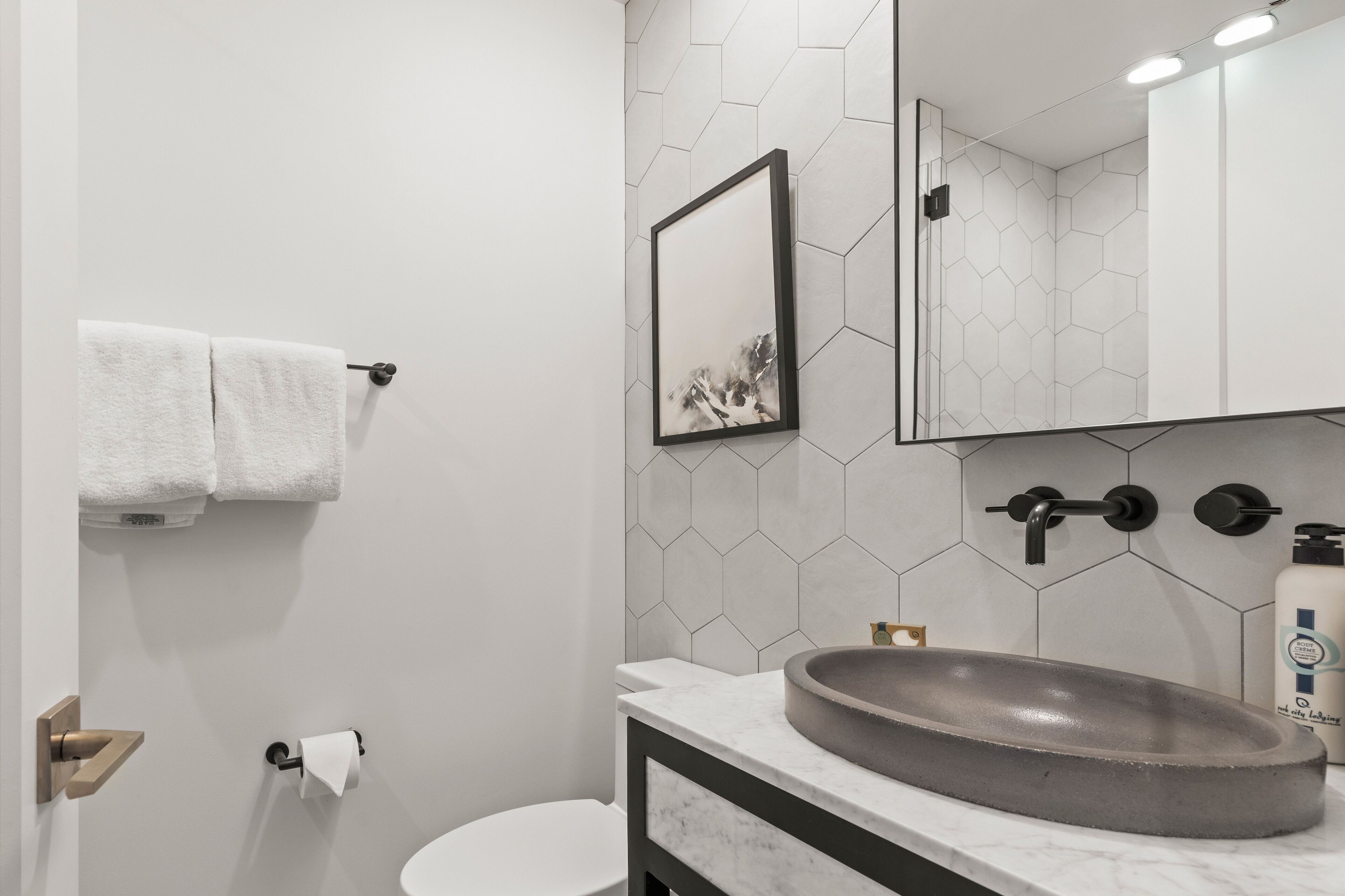 A modern bathroom with a white sink, a toilet, and a towel rack.