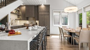 A modern kitchen with a long island, wooden flooring, and a dining area with a table set for six. - Chaparral 204 3 Bedroom Condo (Park City)