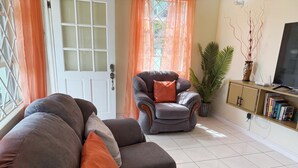 A living room with a sofa, armchair, and a television on a stand. - Peaceful 2BR/1BA modern home, perfect for a laid-back Caribbean getaway (Gros Islet)